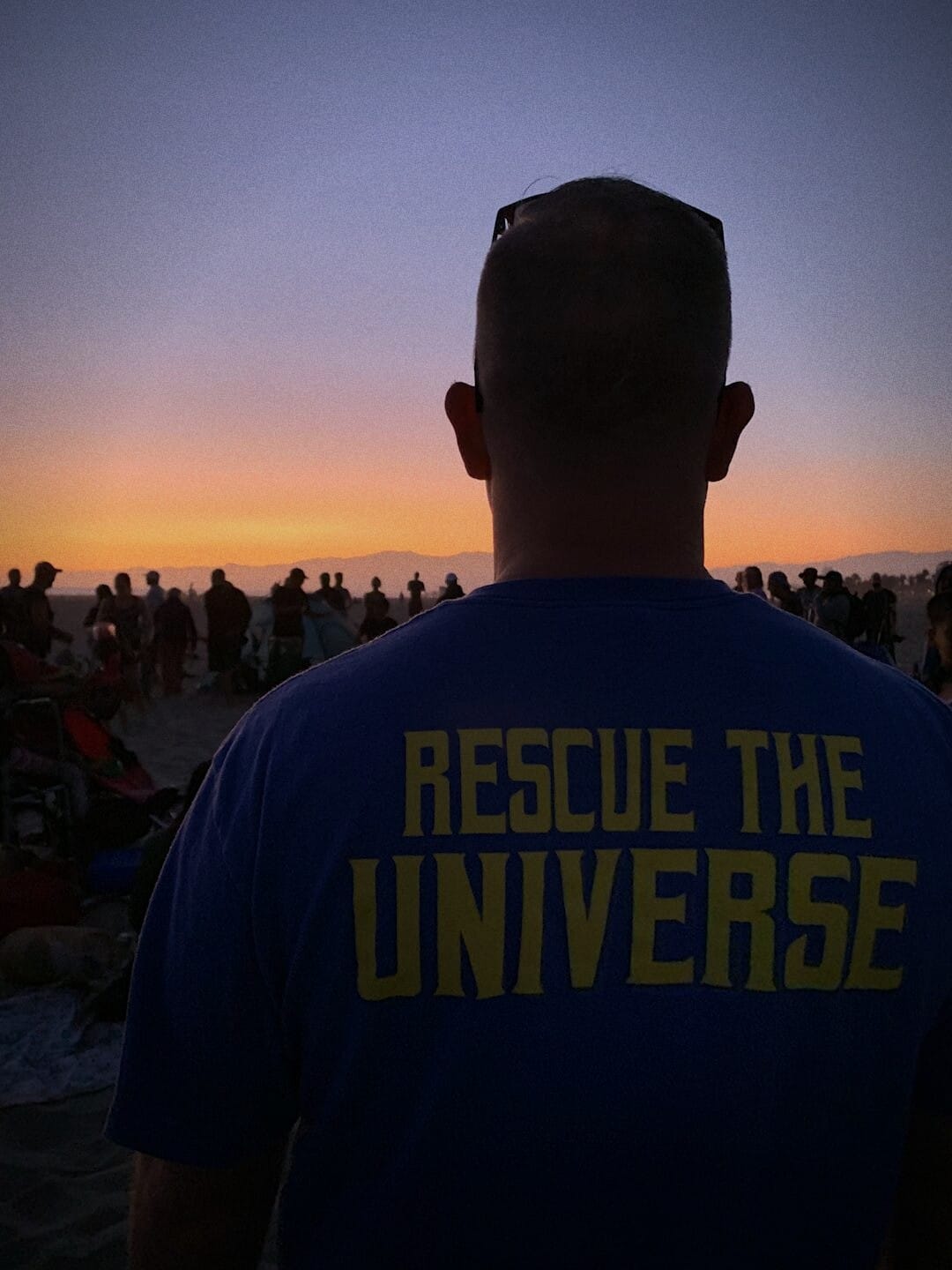 Ryan Nichols from behind at sunset, his shirt reading Rescue the Universe
