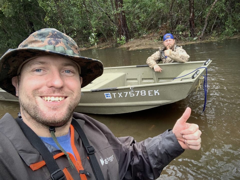 Ryan Nichols in floodwater beside his rescue boat during a hurricane deployment, thumbs up