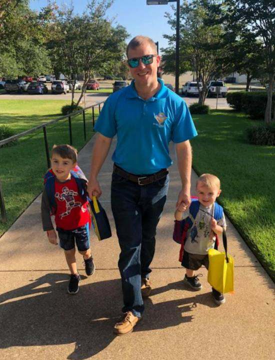 Ryan walking his two young sons to school, holding their hands
